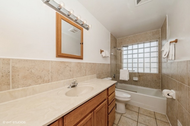 full bathroom with tile patterned floors, toilet, tiled shower / bath, tile walls, and vanity