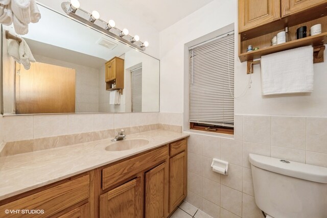 bathroom with vanity, toilet, tile walls, and tile patterned flooring