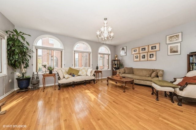 unfurnished living room featuring an inviting chandelier, a healthy amount of sunlight, and light wood-type flooring