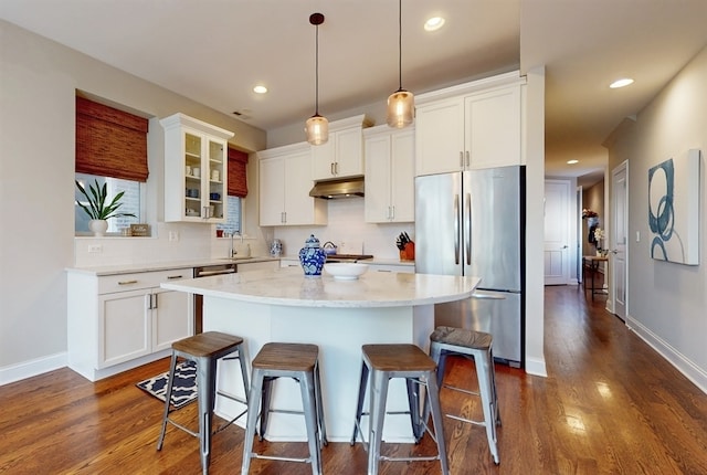 kitchen featuring dark hardwood / wood-style flooring, stainless steel fridge, a kitchen island, and white cabinetry