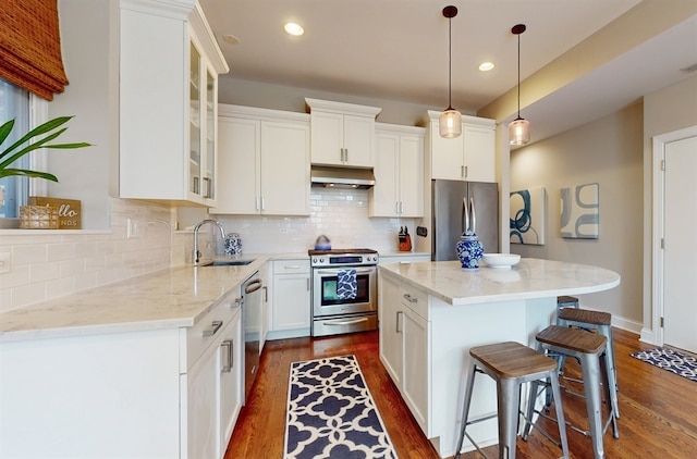 kitchen featuring a center island, light stone countertops, appliances with stainless steel finishes, dark hardwood / wood-style flooring, and white cabinetry