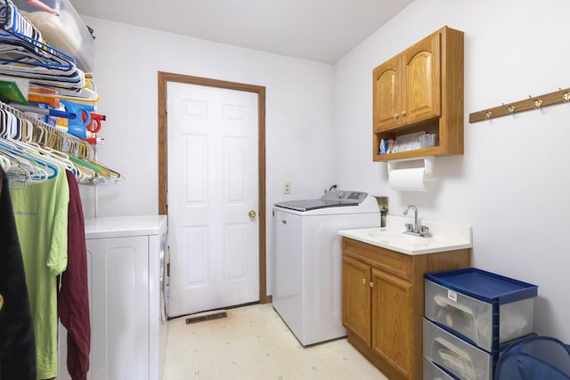 laundry area featuring sink, washing machine and clothes dryer, and cabinets