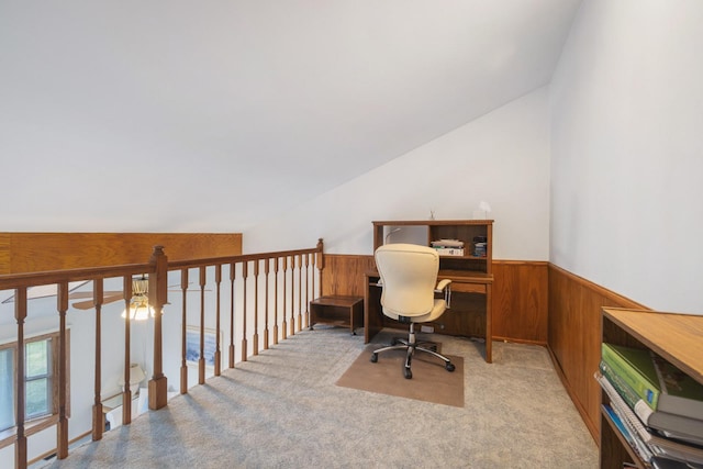 office area featuring vaulted ceiling, light carpet, and wood walls