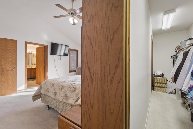 bedroom featuring vaulted ceiling, ceiling fan, light colored carpet, and ensuite bath