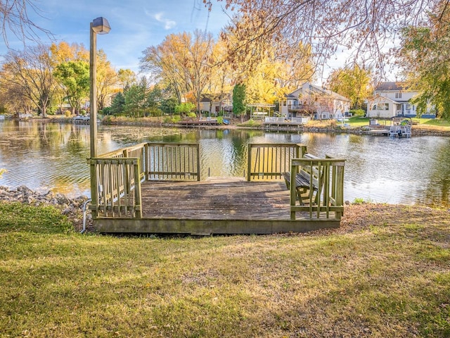 view of dock with a yard and a water view