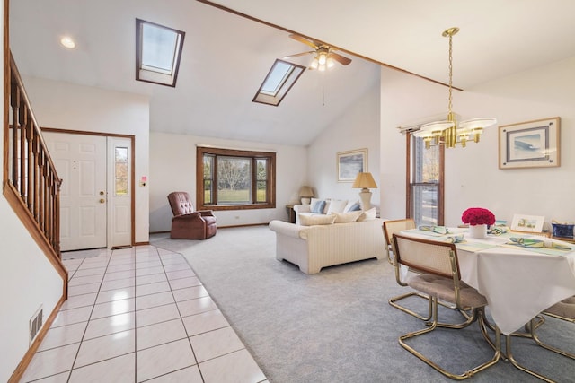 living room with a skylight, ceiling fan with notable chandelier, high vaulted ceiling, and light tile patterned floors