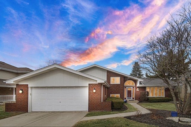 view of front of property featuring an attached garage, driveway, a lawn, and brick siding