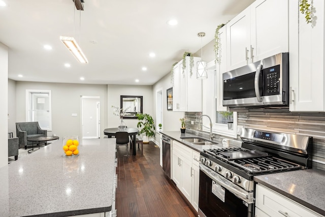 kitchen featuring white cabinets, hanging light fixtures, dark hardwood / wood-style flooring, appliances with stainless steel finishes, and sink