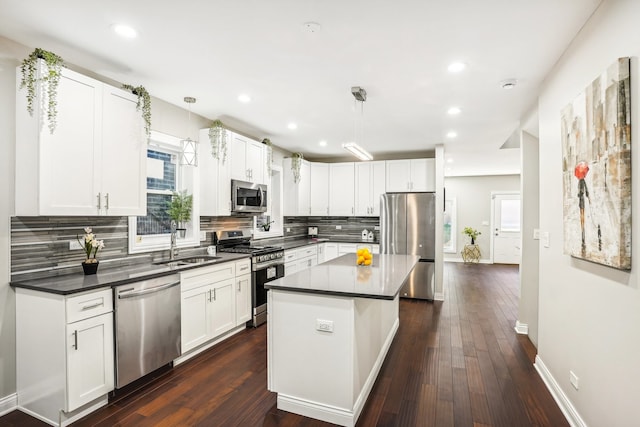 kitchen featuring dark hardwood / wood-style floors, white cabinets, stainless steel appliances, and hanging light fixtures