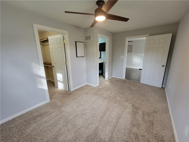 unfurnished bedroom with a spacious closet, carpet, a closet, and ceiling fan