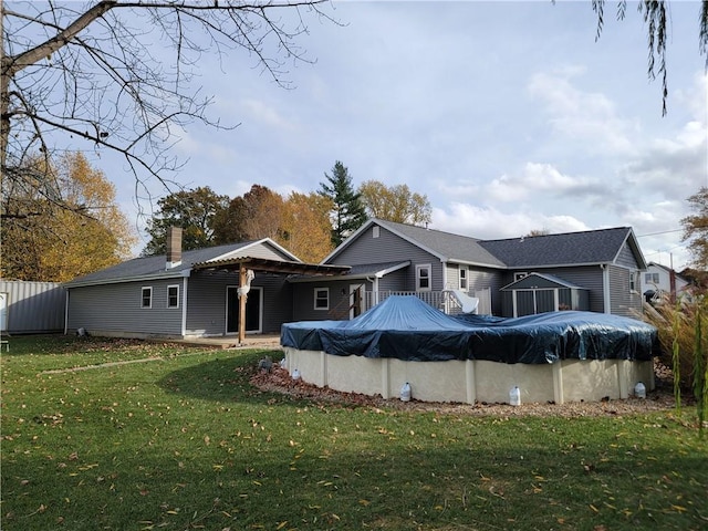 rear view of property with a yard and a covered pool