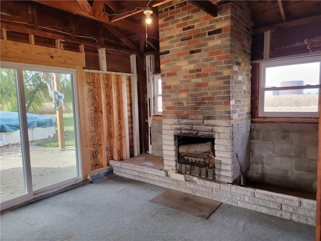 unfurnished living room featuring an outdoor brick fireplace, carpet flooring, and plenty of natural light