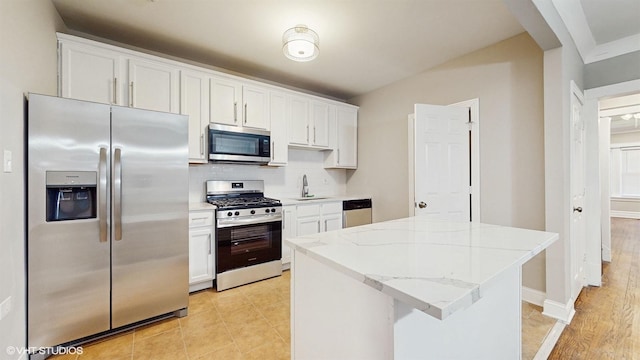 kitchen featuring white cabinets, a center island, stainless steel appliances, decorative backsplash, and sink