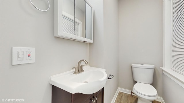 bathroom with hardwood / wood-style flooring, toilet, and vanity