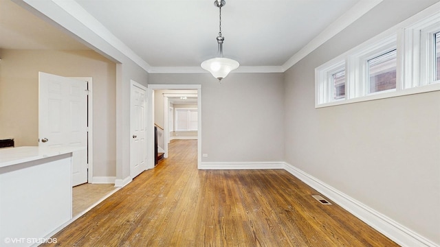 unfurnished dining area featuring hardwood / wood-style floors and crown molding