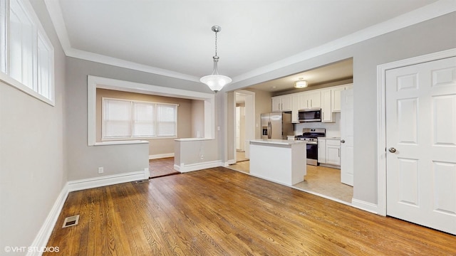 kitchen with white cabinets, stainless steel appliances, hanging light fixtures, and crown molding