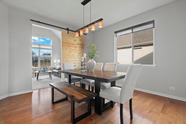 dining area with wood-type flooring and a barn door