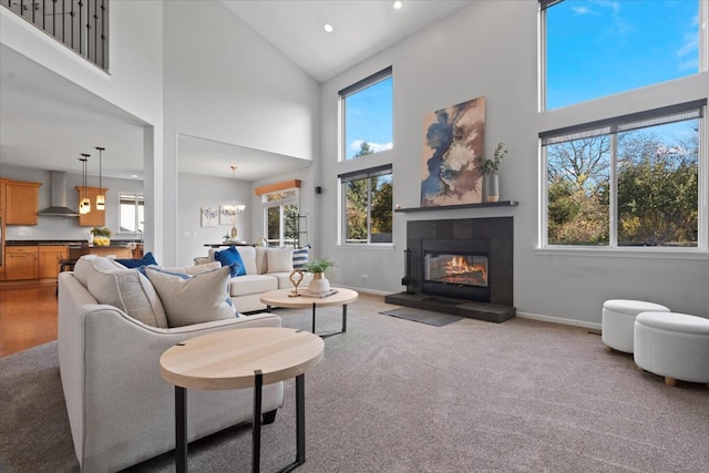 living room featuring light carpet, an inviting chandelier, high vaulted ceiling, and a tiled fireplace