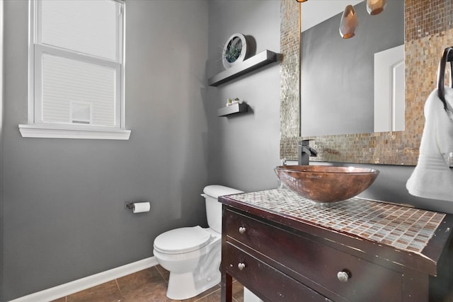 bathroom featuring tile patterned flooring, decorative backsplash, toilet, and vanity