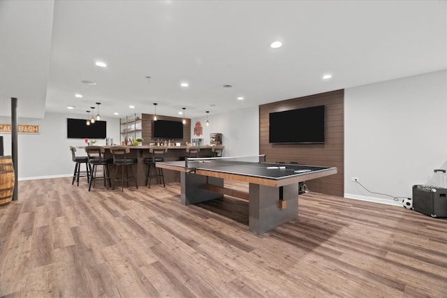 recreation room with indoor bar and light wood-type flooring