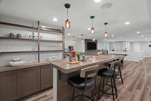 bar with hardwood / wood-style flooring, decorative light fixtures, and dark brown cabinetry