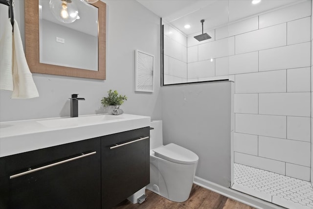 bathroom with tiled shower, toilet, vanity, and hardwood / wood-style flooring