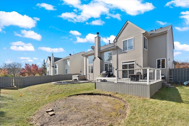 back of house featuring a wooden deck, a jacuzzi, and a yard