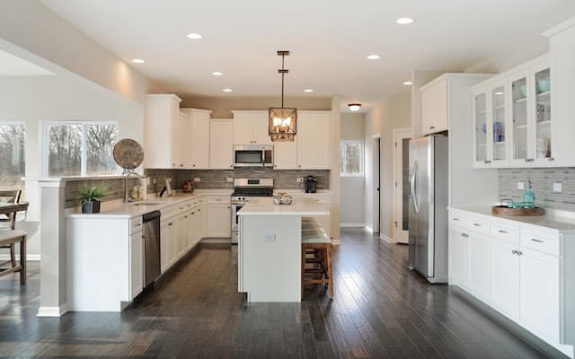 kitchen with appliances with stainless steel finishes, backsplash, dark hardwood / wood-style flooring, hanging light fixtures, and white cabinets