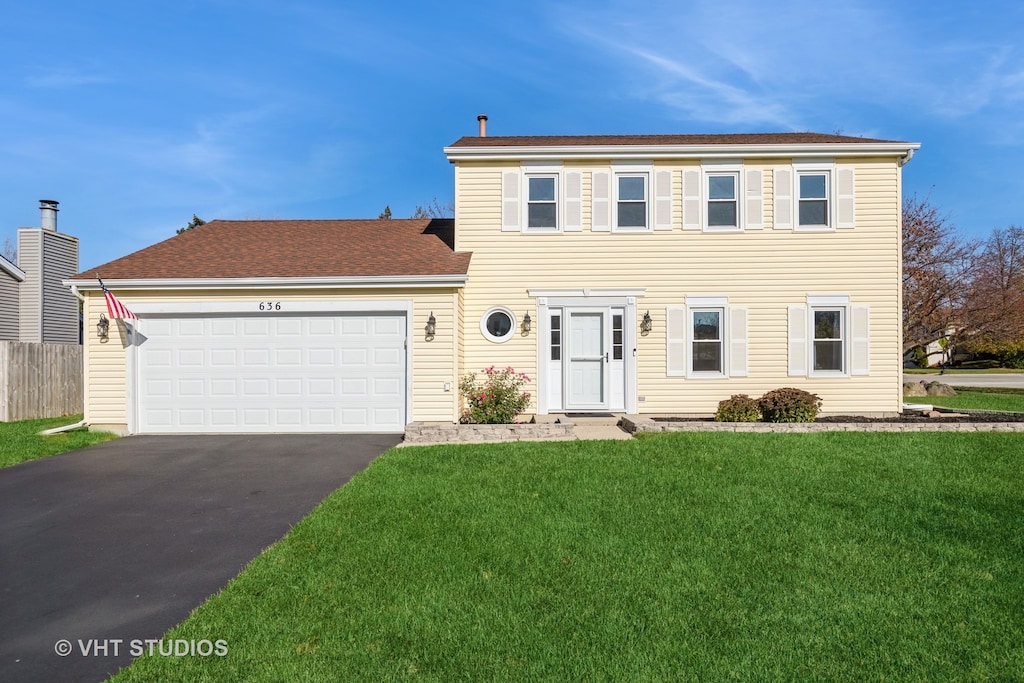 colonial-style house with a garage and a front lawn