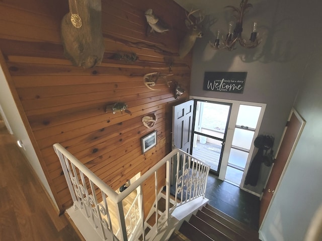 stairs with wood-type flooring and a chandelier