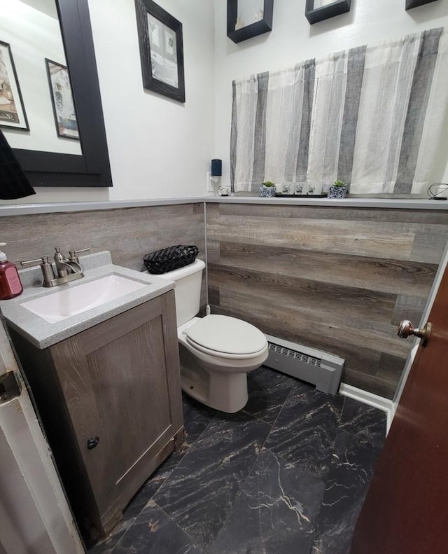 bathroom with baseboard heating, vanity, toilet, and tile walls