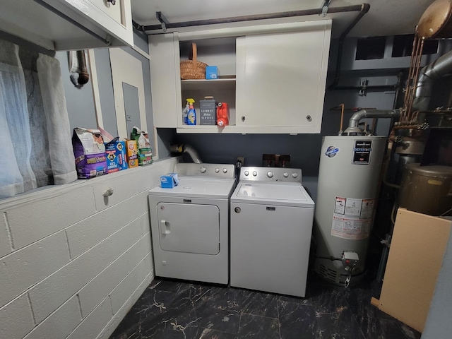 clothes washing area featuring cabinets, washer and clothes dryer, and gas water heater