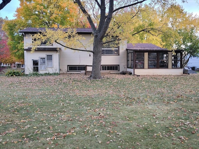 rear view of house featuring a sunroom and a lawn