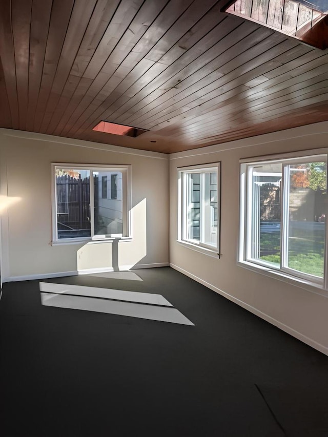 spare room featuring wood ceiling and dark carpet