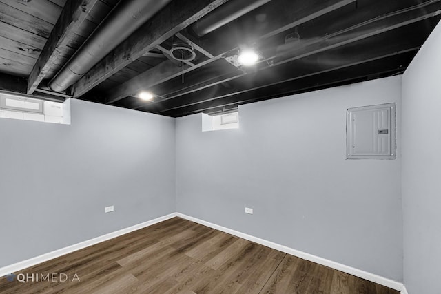 basement featuring hardwood / wood-style flooring and electric panel