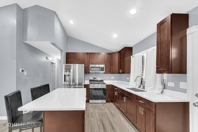 kitchen with a kitchen bar, lofted ceiling, light hardwood / wood-style flooring, a kitchen island, and stainless steel appliances