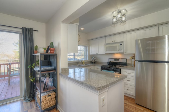 kitchen featuring white cabinetry, appliances with stainless steel finishes, sink, and light stone counters