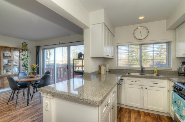 kitchen featuring sink, white cabinetry, dark hardwood / wood-style flooring, kitchen peninsula, and stove