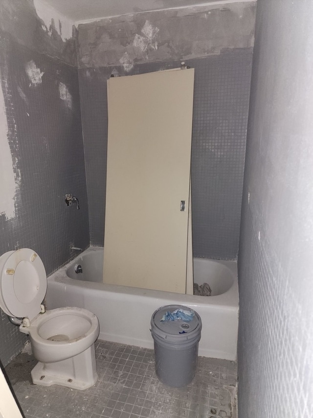 bathroom with toilet, tiled shower / bath, and tile patterned flooring