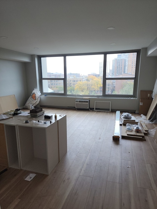 unfurnished office with an AC wall unit, light hardwood / wood-style floors, and a healthy amount of sunlight