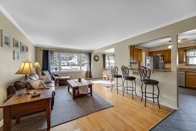 living room featuring sink, crown molding, light hardwood / wood-style flooring, and ceiling fan