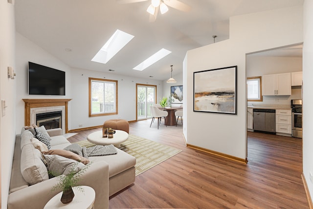 living room with a tile fireplace, light wood-type flooring, high vaulted ceiling, and ceiling fan