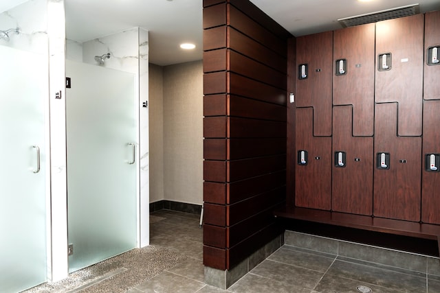 bathroom with a shower with door and tile patterned flooring