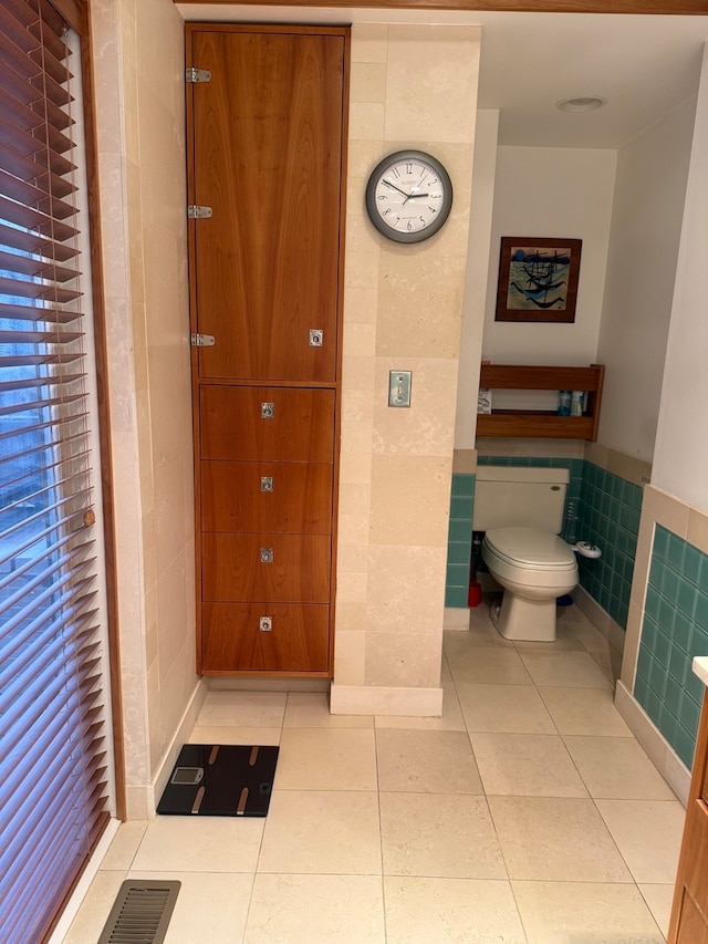 bathroom with tile patterned floors, tile walls, and toilet