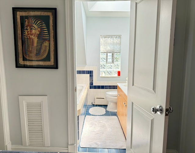 bathroom featuring tile patterned floors, toilet, a bathtub, vanity, and tile walls