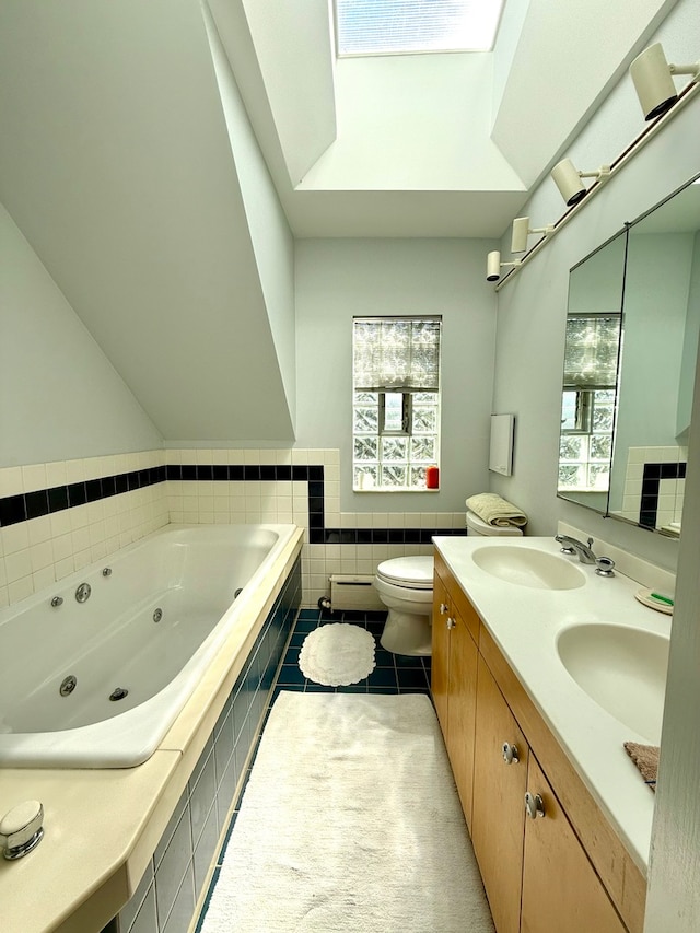 bathroom with tiled tub, a wealth of natural light, vanity, and toilet