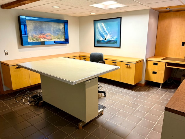 tiled home office with a drop ceiling and built in desk