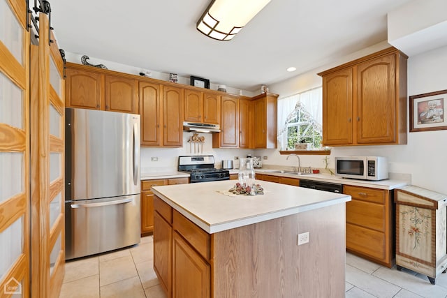 kitchen featuring appliances with stainless steel finishes, sink, a barn door, a kitchen island, and light tile patterned floors