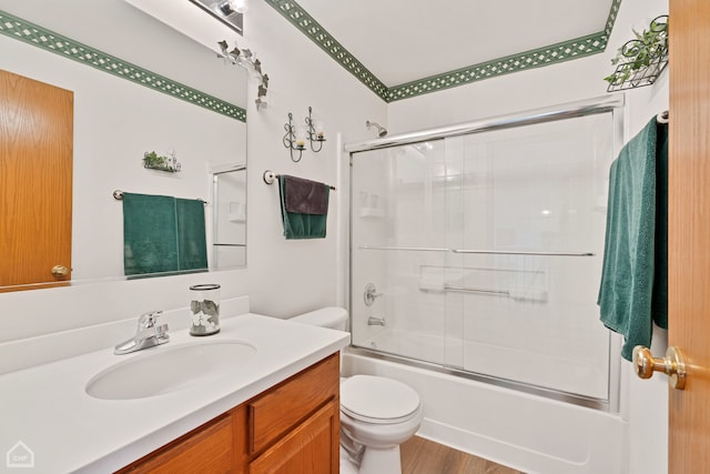 full bathroom with vanity, combined bath / shower with glass door, hardwood / wood-style flooring, and toilet