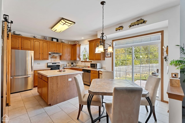 kitchen featuring appliances with stainless steel finishes, sink, a center island, pendant lighting, and light tile patterned floors